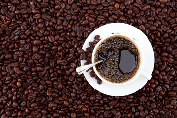 A cup of coffee and brown beans