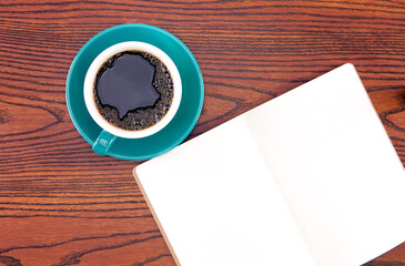 A cup of black coffee and a blank notebook