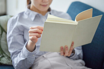 リビングでリラックスして本を読む女性