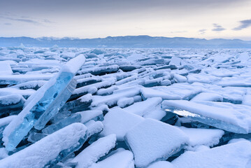 Endless hummock field on the frozen Lake Baikal. Piles of snow-covered debris of blue ice on a frosty day. Cold natural background. Unusual winter landscape