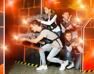 Ordinary Laser tag players young mens and womens playing in teams in dark laser tag station. High quality photo