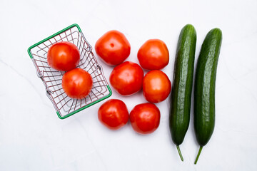 Tomatoes and cucumbers in the grocery basket and on the table