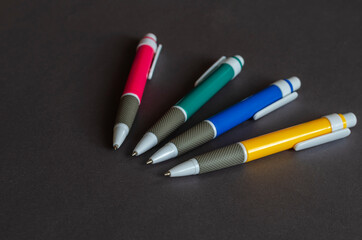 Four multi-colored pens on a gray background.