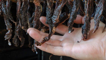 Hanging beef jerky and male hand close up.