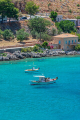 Fototapeta na wymiar view of Limeni village with fishing boats in turquoise waters and the stone buildings as a background in Mani, South Peloponnese , Greece.
