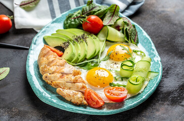 Breakfast with chicken grilled fillet with salad fresh tomatoes, cucumbers, eggs and avocado. Keto Paleo diet menu. top view