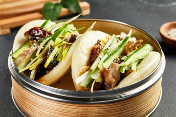 Bao bun with roast duck. Bamboo steamer on dark slate table. Chinese, asian, authentic food concept