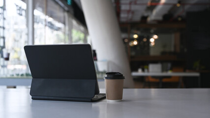 Mock up digital tablet with wireless keyboard and coffee cup on white table in modern office.