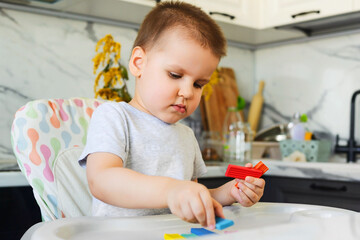 Child sculpts a figure of a flower of seven colors of colored clay. Home education of the child at...