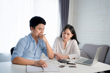 Fototapeta premium Young Asian couples are calculating their income. They are stressed