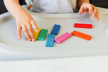 Child sculpts a figure of a flower of seven colors of colored clay. Home education of the child at...