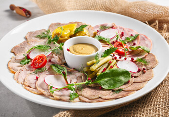 Cold Cut Meat Platter. Rustic style meat appetizers with dip and vegetables. Snack plate on grey table with sack napkin.