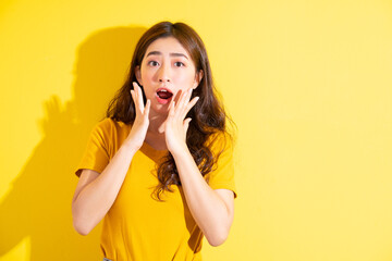 Young Asian girl posing on yellow background