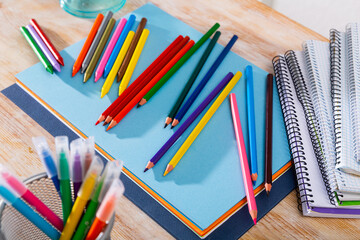Picture of multicolored pencils on table with papers and notebooks