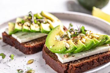 healthy toasts with avocado, cheese and whole wheat rye bread on a plate. tasty Italian meal. Top view
