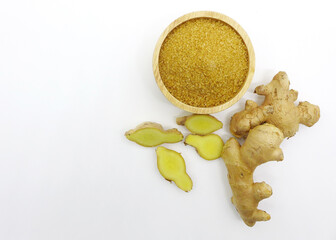 Finely ground dry ginger in wooden bowl isolated on white background from above. Fresh whole and sliced root ginger.