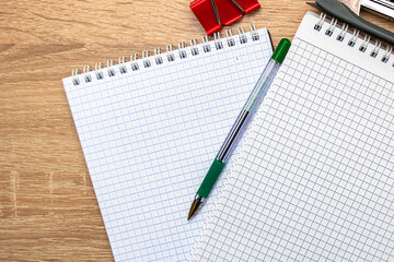 two notepads a paper clip a stapler and a fountain pen are on the table