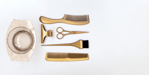 Golden hairdresser tools on a white background, scissors, comb, clip, brush and bowl. Hair salon accessories, template with space for text.