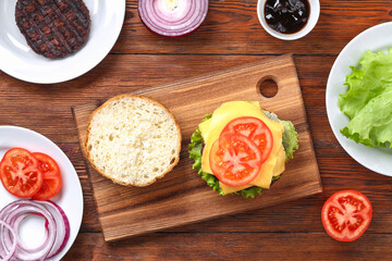 Homemade hamburger with cutlet, salad, onion, tomato and cheese. Cheeseburger, burger. Step by step. Top view. Cooking a burger