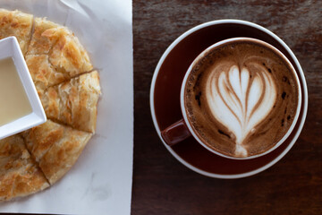 Top view of a hot cup of latte art coffee on dark wooden table.