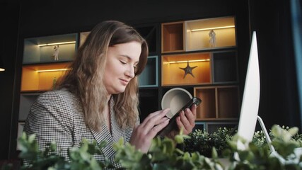  young business woman uses the phone. Attractive woman scrolling pages, tapping on touchscreen, checking news and financial charts