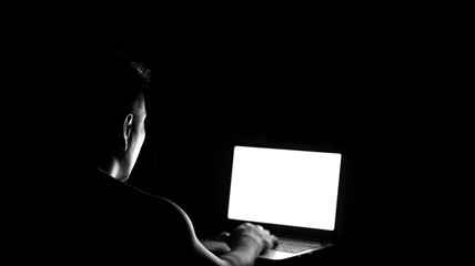 Naklejka premium Low key silhouette of male profile watching at laptop screen
