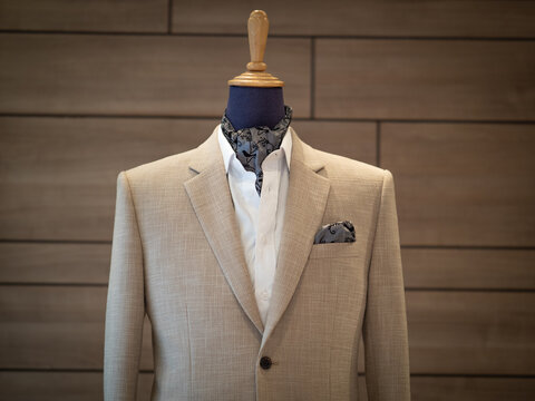 Close up of beige jacket suit with white shirt and ascot tie scarf on mannequin. selective focus