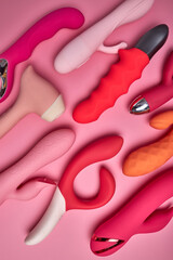 different red and pink adult sex toys on pink background, toys intended for females intimate life,...