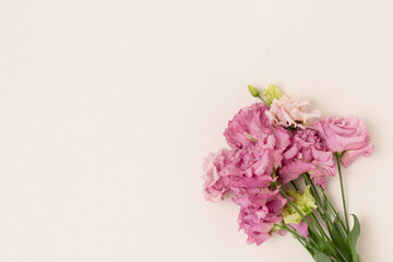 Fototapeta na wymiar Bouquet of eustoma flowers on a beige background. Minimal composition with copyspace. Gift for Womans Day.