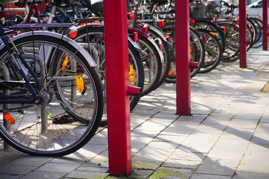 many bicycles on a covered bicycle parking lot next to a car park in the city center at the train station