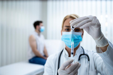 Close up view of the doctor holding bottle and syringe and preparing vaccine shot for the patient during corona virus epidemic.