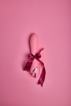 Adult gift for couples. Close up photo of pink cute dildo vibrator, accessory for sex games wrapped in red bow as present