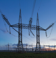 High voltage electric pole and transmission lines in the evening. Electricity pylons at sunset. Power and energy. Energy conservation. High voltage grid tower with wire cable at distribution station.