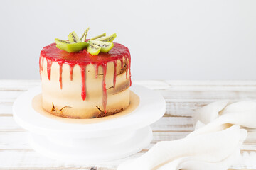 Gluten-free cake with strawberry icing, coconut chips and almonds on a white cake pan, close-up. Copy space.