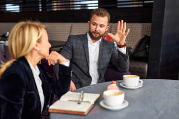 Fototapeta premium entrepreneur and manager have conversation over a cup of coffee in restaurant, representative business man and pretty blond adult woman in formal wear sit at table talking