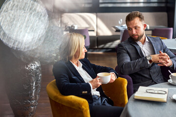 female traveller on business meeting listening to her male colleague, they enjoying coffee and...