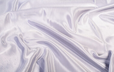 Abstract background from shiny satin lilac, purple fabric. Wavy fabric
