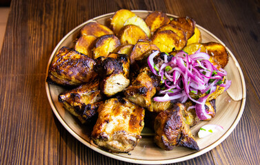 Grilled meat with fried potatoes and vegetables and onions
