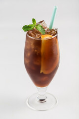 Cold coffee with ice, orange and mint in a glass glass on a white background, isolated.