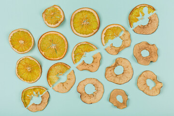 A pattern of dried orange and apple rings on a turquoise background. Healthy snacks for children's food.