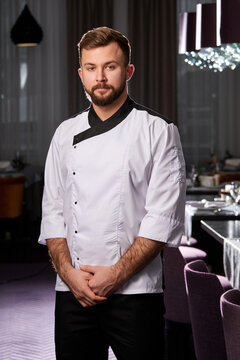 Professional Male Chef Or Cook In White Apron Or Uniform Posing, Confidently Looking At Camera, Restaurant Staff After Work, Take Break. Hotel Restaurant