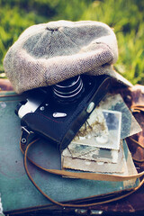 Close-up of an old camera with a vintage hat and retro photos on a wooden background.
