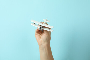 Female hand hold toy plane on blue background