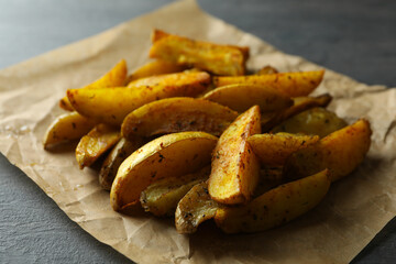 Baking paper with potato wedges on dark textured background