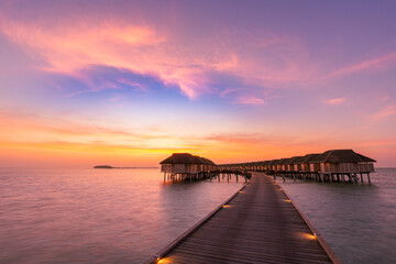 Fototapeta na wymiar Amazing panoramic sunset Maldives. Luxury resort villas seascape with soft led lights under colorful sky. Beautiful twilight sky and colorful clouds. Beautiful beach background for vacation holiday