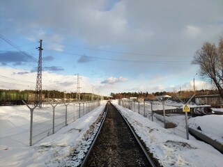 Fototapeta na wymiar rails in the snow. railway track enclosed by a barbed wire fence