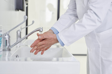Cropped Doctor washing Hands Before Operation, Side View. Man In Medical Suit disinfecting hands during coronavirus spreading