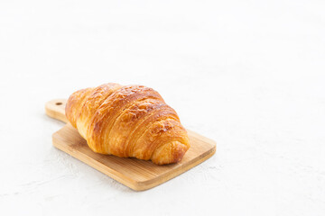 Croissant on a wooden board on a white background.