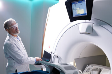 Senior Radiologist Controls MRI or CT or PET Scan with Male Patient Undergoing Procedure. High-Tech...
