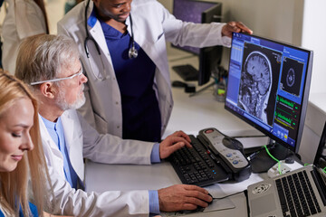 In Control Room Senior Doctor and Radiologist Discuss Diagnosis Using Monitors Showing Brain Scans...